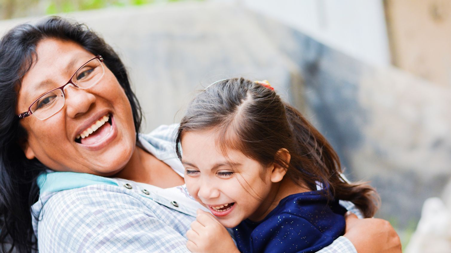 Adult and child smiling while embracing.